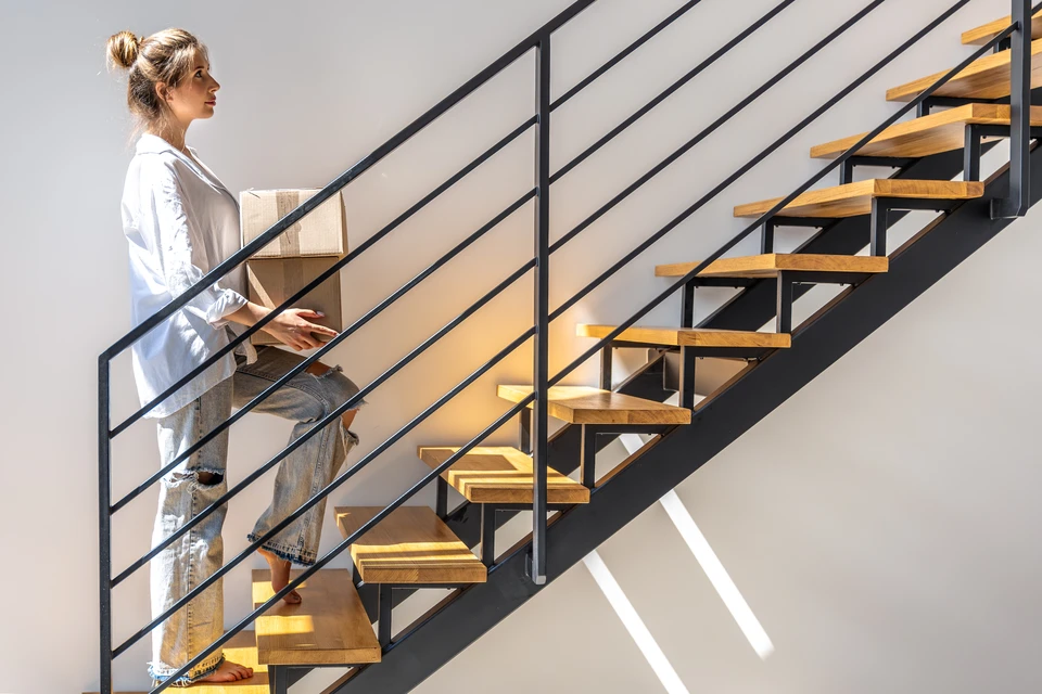 Intérieur moderne avec escalier suspendu à structure métallique noire et marches en bois foncé, rampe avec main courante en bois